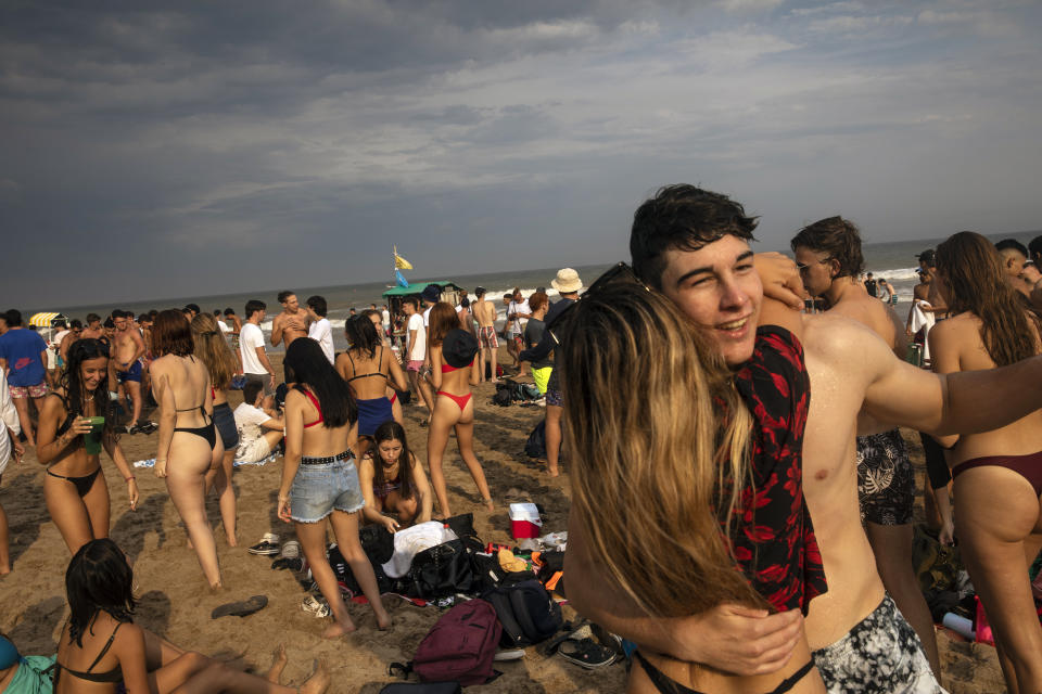 Teenagers dance late afternoon at the beach in Pinamar, Buenos Aires province, Argentina, Saturday, Jan. 15, 2022. Amid a rebound in infections by the new Omicron variant of COVID 19, thousands of vacationers in Argentina fill the beaches in one of the hottest summers in recent years. (AP Photo/Rodrigo Abd)