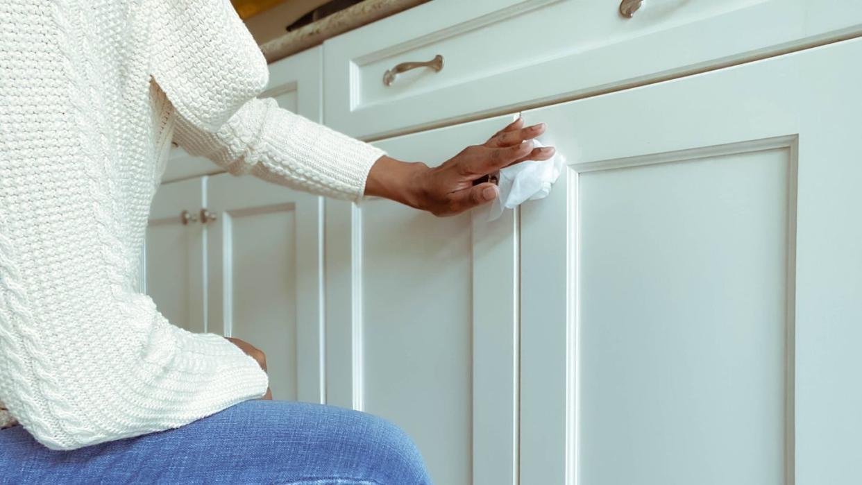 cleaning kitchen cabinets, close up of woman cleaning kitchen cabinet