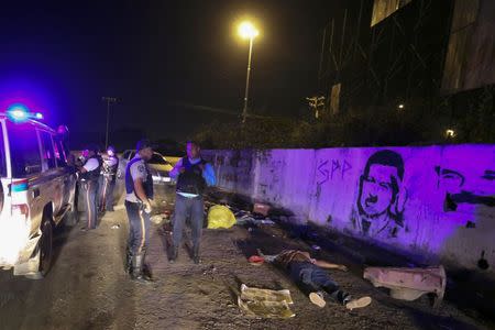 Police officers stand near the body of Anzoategui state policeman Mario Figueroa after he was shot dead in Barcelona, in the state of Anzoategui January 24, 2015. REUTERS/Stringer