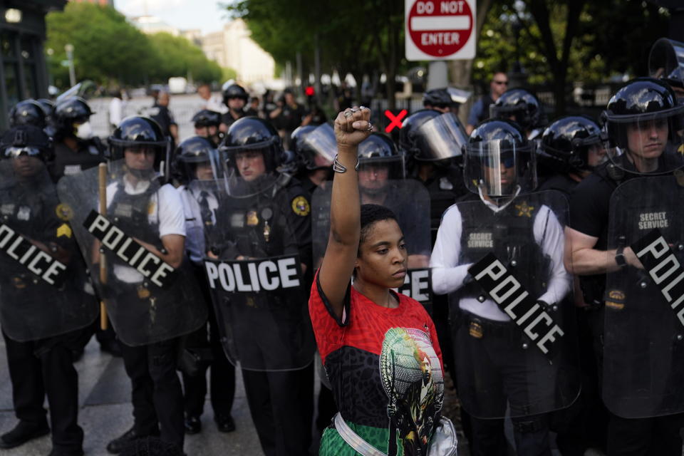 FILE - In this May 30, 2020, file photo, a demonstrator raises their fist as others gather to protest the death of George Floyd near the White House in Washington. Floyd died after being restrained by Minneapolis police officers. Black activists are coming out strongly against a growing narrative among conservatives that equates last week’s deadly siege on the U.S. Capitol to last summer’s Black Lives Matter protests over racial injustice. (AP Photo/Evan Vucci, File)