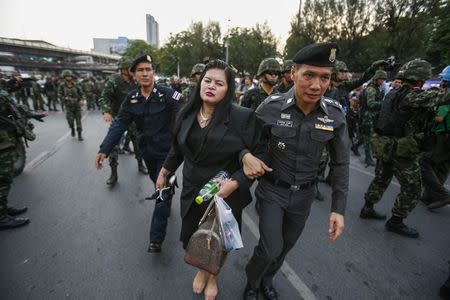 A policeman and soldiers lead a woman who showed her support for the army to safety and away from protesters against military rule at Victory monument in Bangkok in this May 26, 2014 file photo. REUTERS/Athit Perawongmetha/Files
