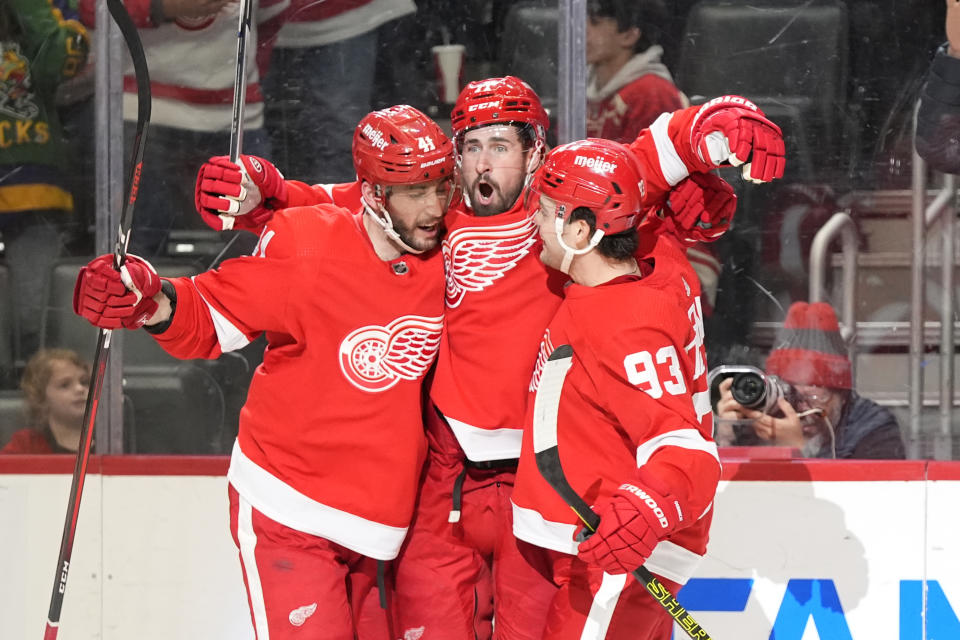 Detroit Red Wings center Dylan Larkin, is hugged by defenseman Shayne Gostisbehere (41) and right wing Alex DeBrincat (93) after his goal during the second period of an NHL hockey game against the Philadelphia Flyers, Thursday, Jan. 25, 2024, in Detroit. (AP Photo/Carlos Osorio)