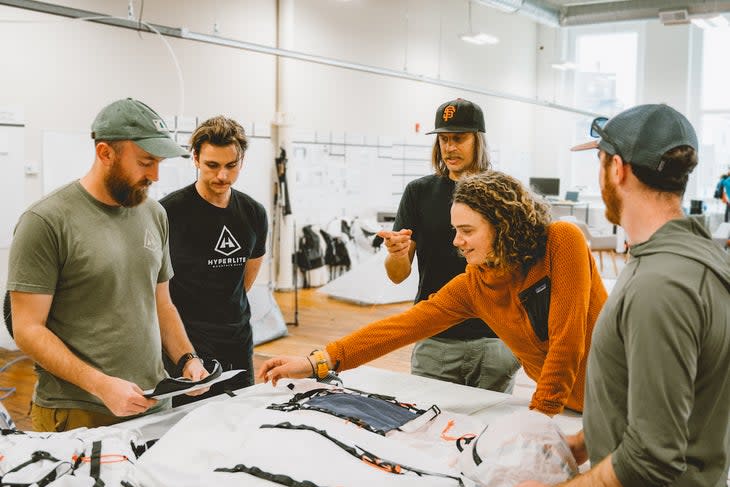 Pro skier Cody Townsend with group of HMG product designers standing over pieces of the HMG Crux pack at HMG headquarters