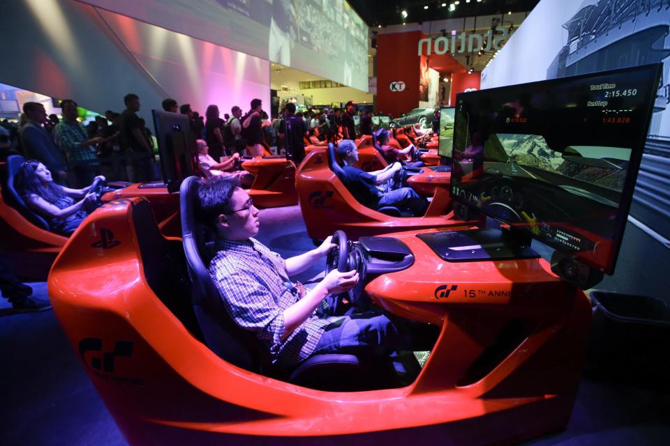 Show attendees play the popular racing game, "Gran Turismo," in simulators at the Sony booth during the Electronic Entertainment Expo in Los Angeles, Tuesday, June 11, 2013. (AP Photo/Jae C. Hong)