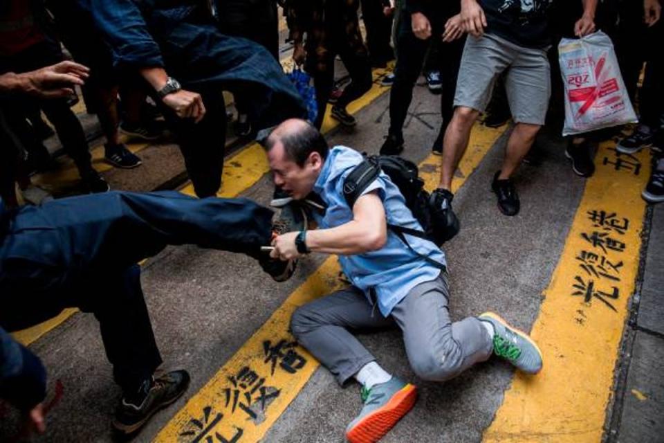 A man (C) is beaten after getting in an argument during a demonstration of office workers and protesters, in Central in Hong Kong during 2019 protests (AFP via Getty Images)