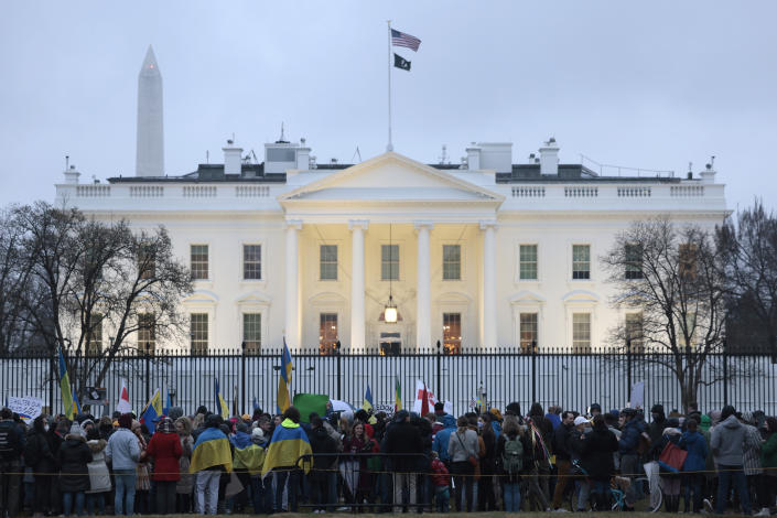 Antiwar demonstrators gather in front of the White House, where the U.S. flag is flying.