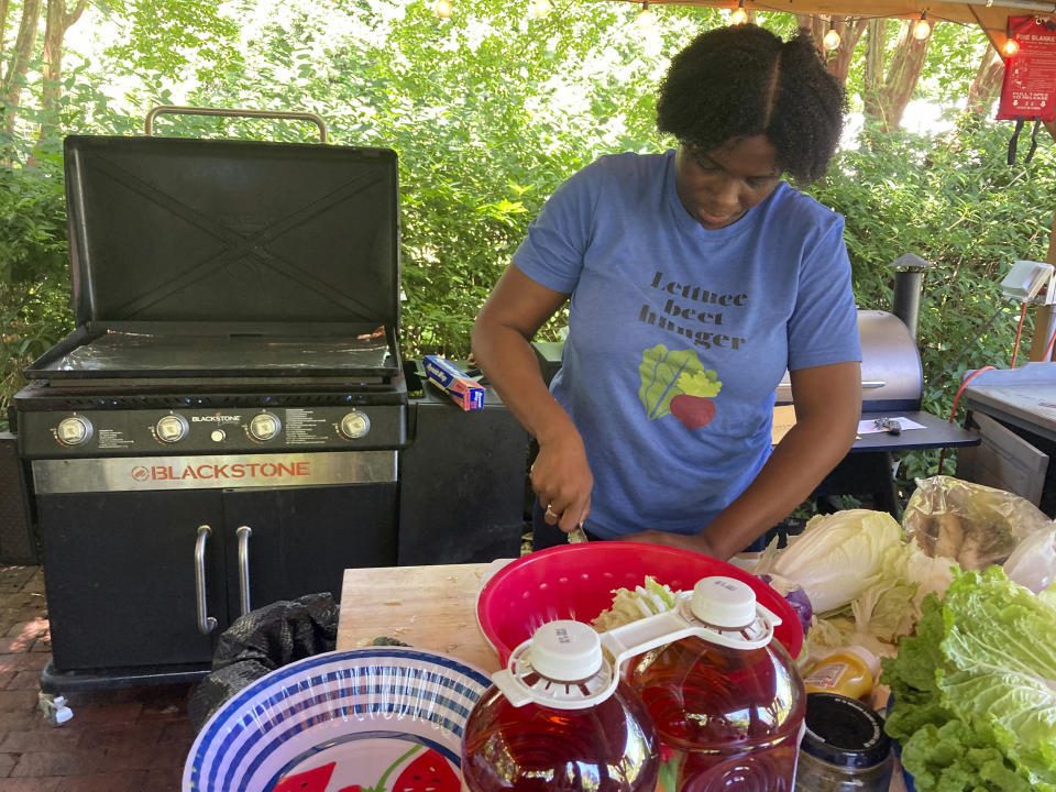 Chef Shanetta Edwards prepares a lunch in the outdoor kitchen with bounty from the Spring Forest farm in Hillsborough, North Carolina, on May 29, 2024. This farm grows food, supports refugee resettlement and provides outdoor retreats for people in the healing professions. (Yonat Shimron/Religion News Service via AP)