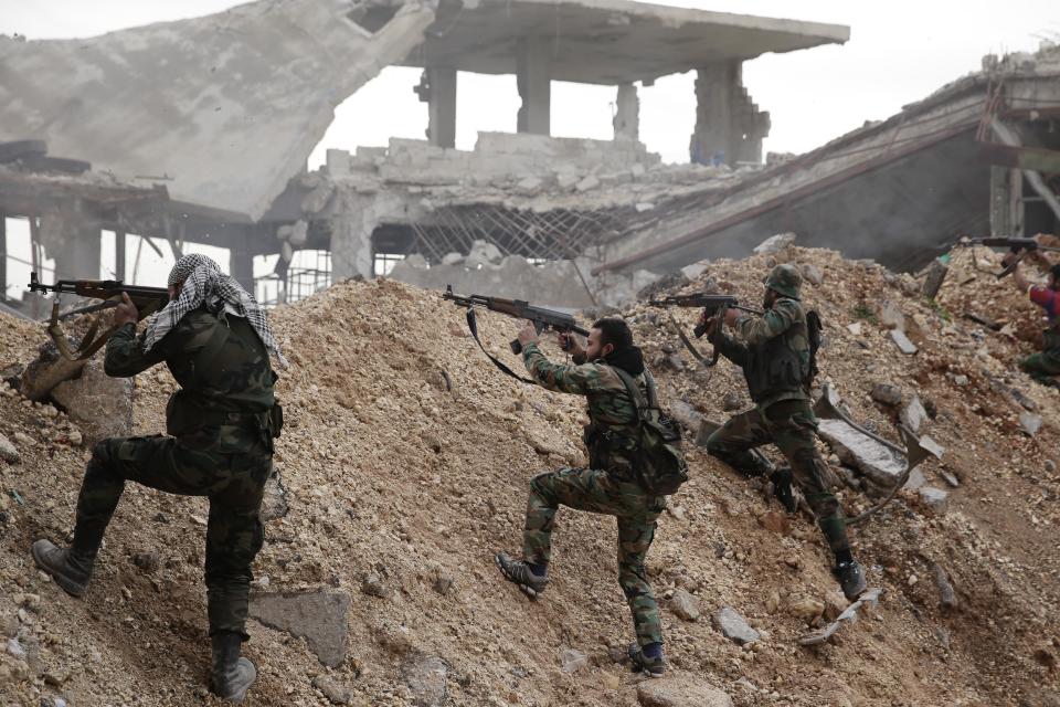 FILE - In this Dec. 5, 2016 file photo, Syrian army soldiers fire their weapons during a battle with rebel fighters at the Ramouseh front line, east of Aleppo, Syria. In a world gripped by a pandemic, global unrest and a fast-moving news cycle, it can be difficult to remember that the war in Syria is still happening. (AP Photo/Hassan Ammar, File)