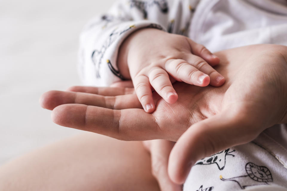 Adult hand holding a baby's hand, conveying a sense of care and protection