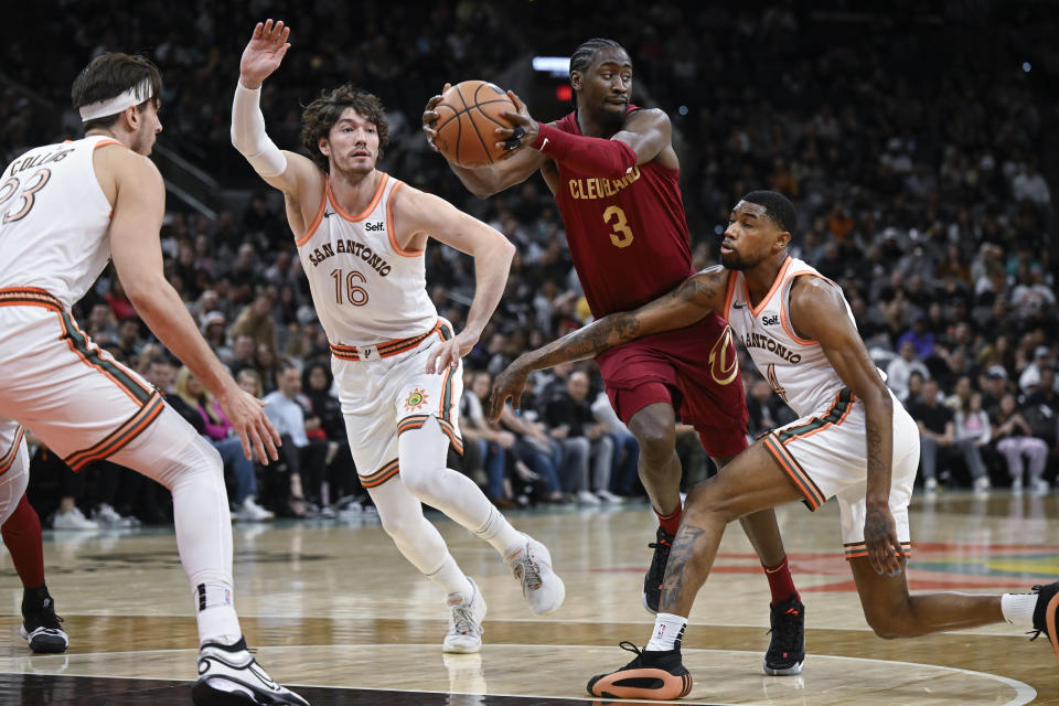 Cleveland Cavaliers' Caris LeVert (3) looks to pass the ball as he is defended by San Antonio Spurs' Blake Wesley, right, Cedi Osman (16) and Zach Collins, left, during the first half of an NBA basketball game, Saturday, Feb. 3, 2024, in San Antonio. (AP Photo/Darren Abate)