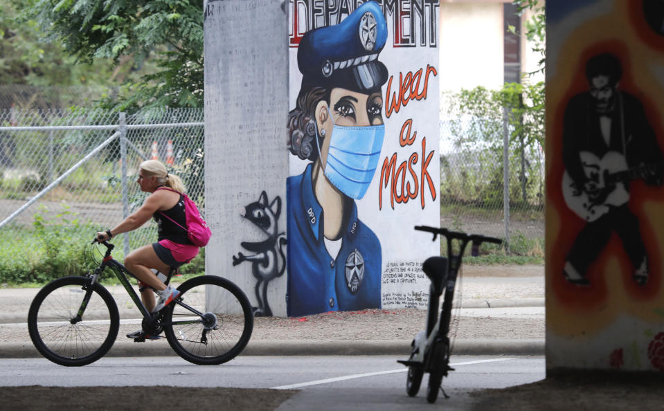 A bicyclist passes by a COVID-19 related wall painting in the Deep Ellum section of Dallas, Tuesday, June 30, 2020. (AP Photo/LM Otero)