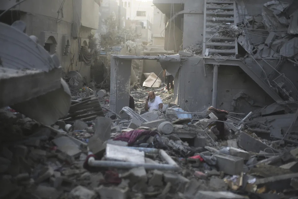 A Palestinian talks on the phone in by the buildings destroyed in the Israeli bombardment of the Gaza Strip in Rafah on Sunday, Oct. 22, 2023. (AP Photo/Hatem Ali)