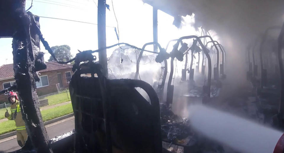 A still from the inside of the bus, showing how everything was charred, while a firefighter continues to hose down the flames.