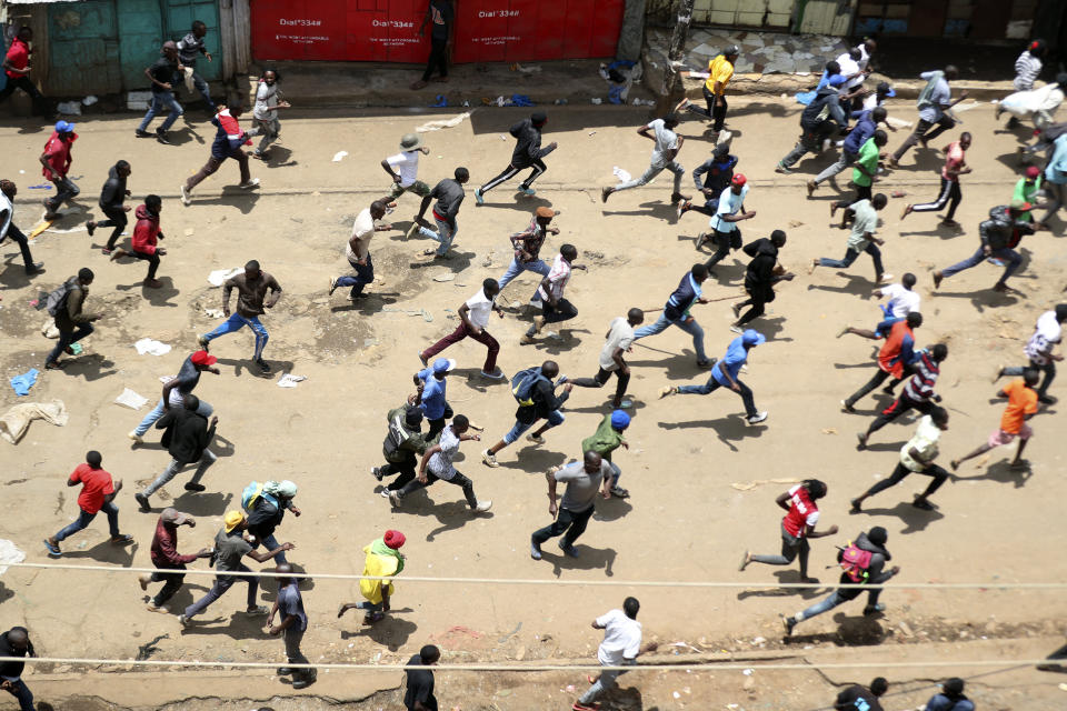 Protesters run towards riot police officers during a mass rally called by the opposition leader Raila Odinga over the high cost of living in Kibera Slums, Nairobi, Monday, March 27, 2023. Police in Kenya are on high alert ahead of the second round of anti-government protests organized by the opposition that has been termed as illegal by the government. Police chief Japheth Koome insists that Monday's protests are illegal but the opposition leader Raila Odinga says Kenyans have a right to demonstrate.(AP Photo/Brian Inganga)