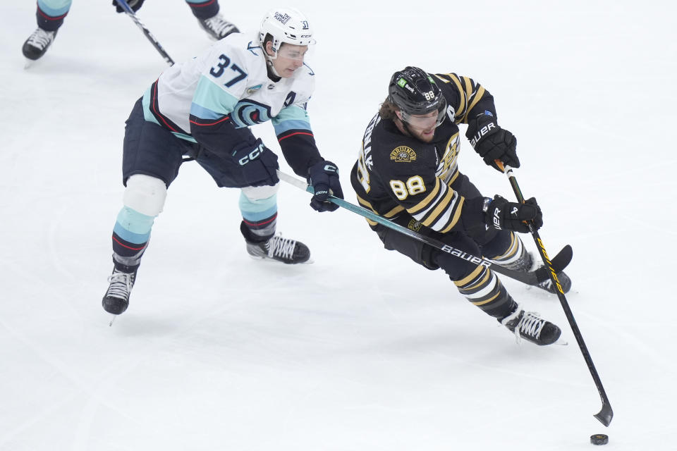 Seattle Kraken center Yanni Gourde (37) and Boston Bruins forward David Pastrnak (88) pursue the puck in the first period of an NHL hockey game, Thursday, Feb. 15, 2024, in Boston. (AP Photo/Steven Senne)