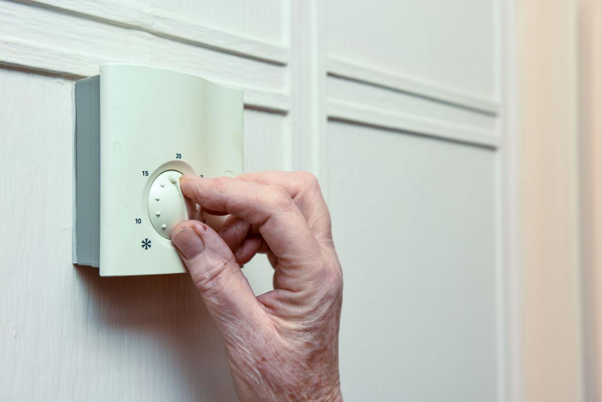 Mature woman turns down the central heating at home to save money