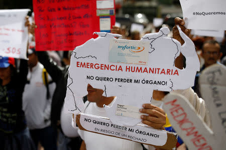 Reinaldo Olivares, a kidney transplanted patient, holds a placard with the shape of the map of Venezuela that reads, "Humanitarian emergency. I do not want to lose my organ", during a protest against medicinal shortages in Caracas, Venezuela February 8, 2018. REUTERS/Carlos Garcia Rawlins