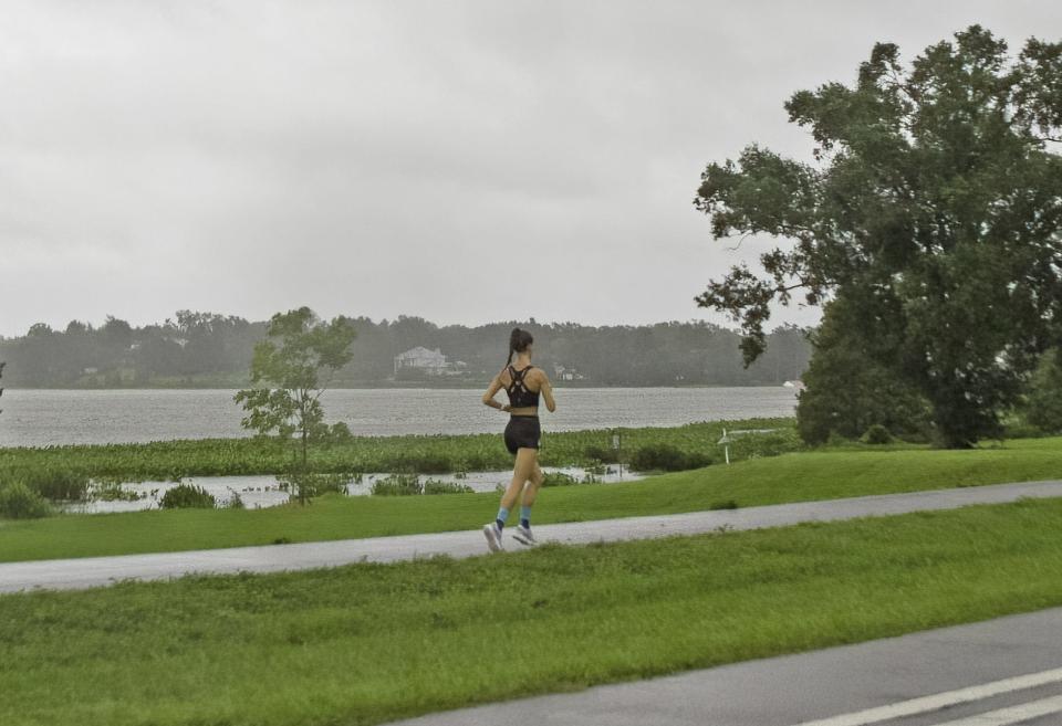A woman runs Wednesday morning on the Lake Hollingsworth Trail in Lakeland as an outer band from Hurricane Idalia brought rain to the area.