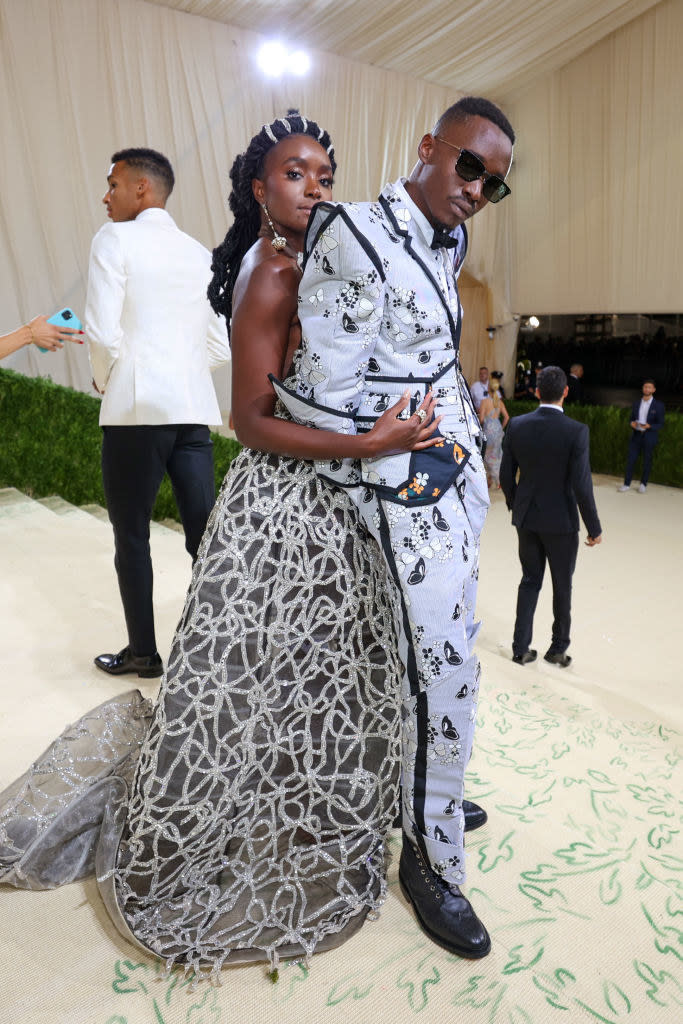 KiKi Layne wears a dark sparkly strapless gown and Ashton Sanders wears a light colored suit with dark butterflies on it