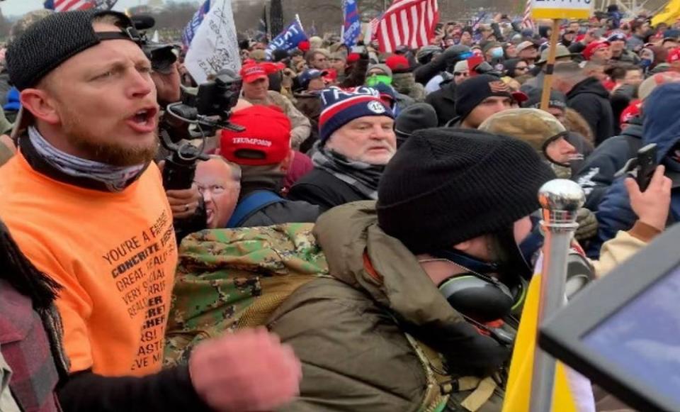 Dustin Ray Williams (far left, in orange) was arrested on felony and misdemeanor charges including obstruction of law enforcement during civil disorder and violence toward officers at the Jan. 6 U.S. Capitol riot.