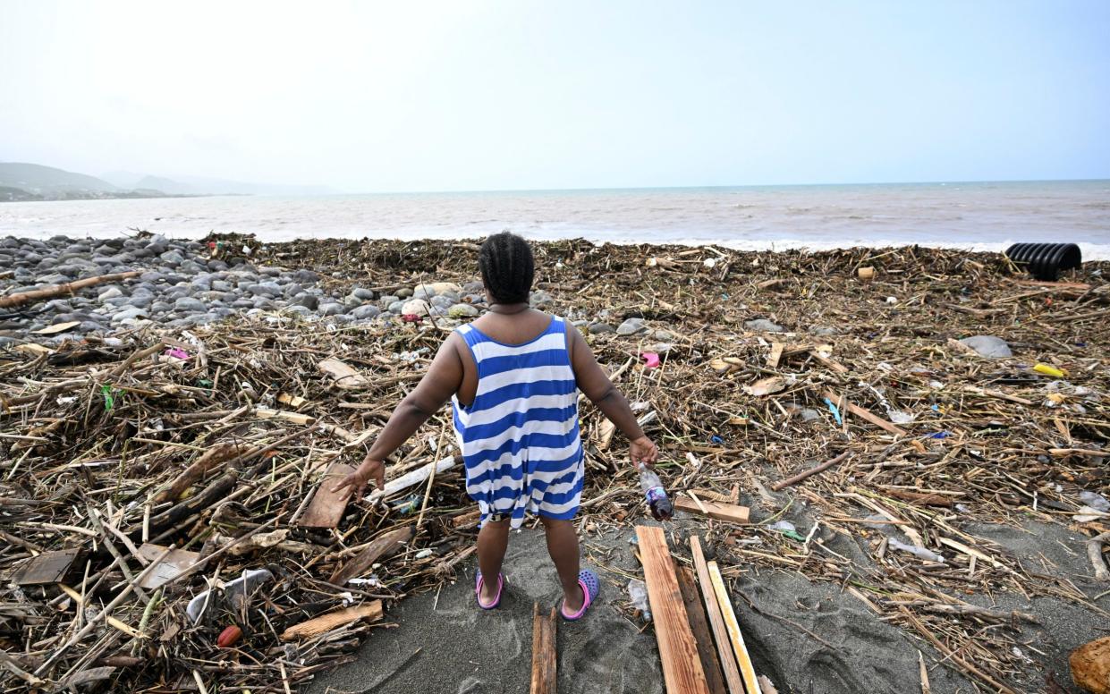 A woman looks at a beach littered with trash at Bull Bay, Jamaica, in the aftermath of Hurricane Beryl