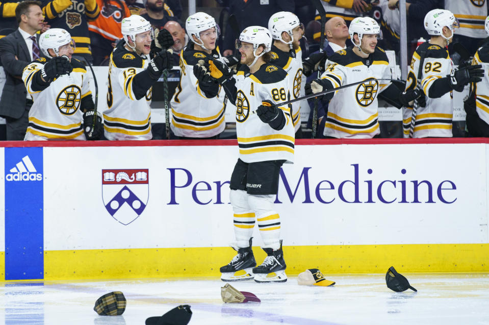 Boston Bruins' David Pastrnak, center, celebrates his third goal of the game with teammates during the third period of an NHL hockey game against the Philadelphia Flyers, Sunday, April 9, 2023, in Philadelphia. (AP Photo/Chris Szagola)