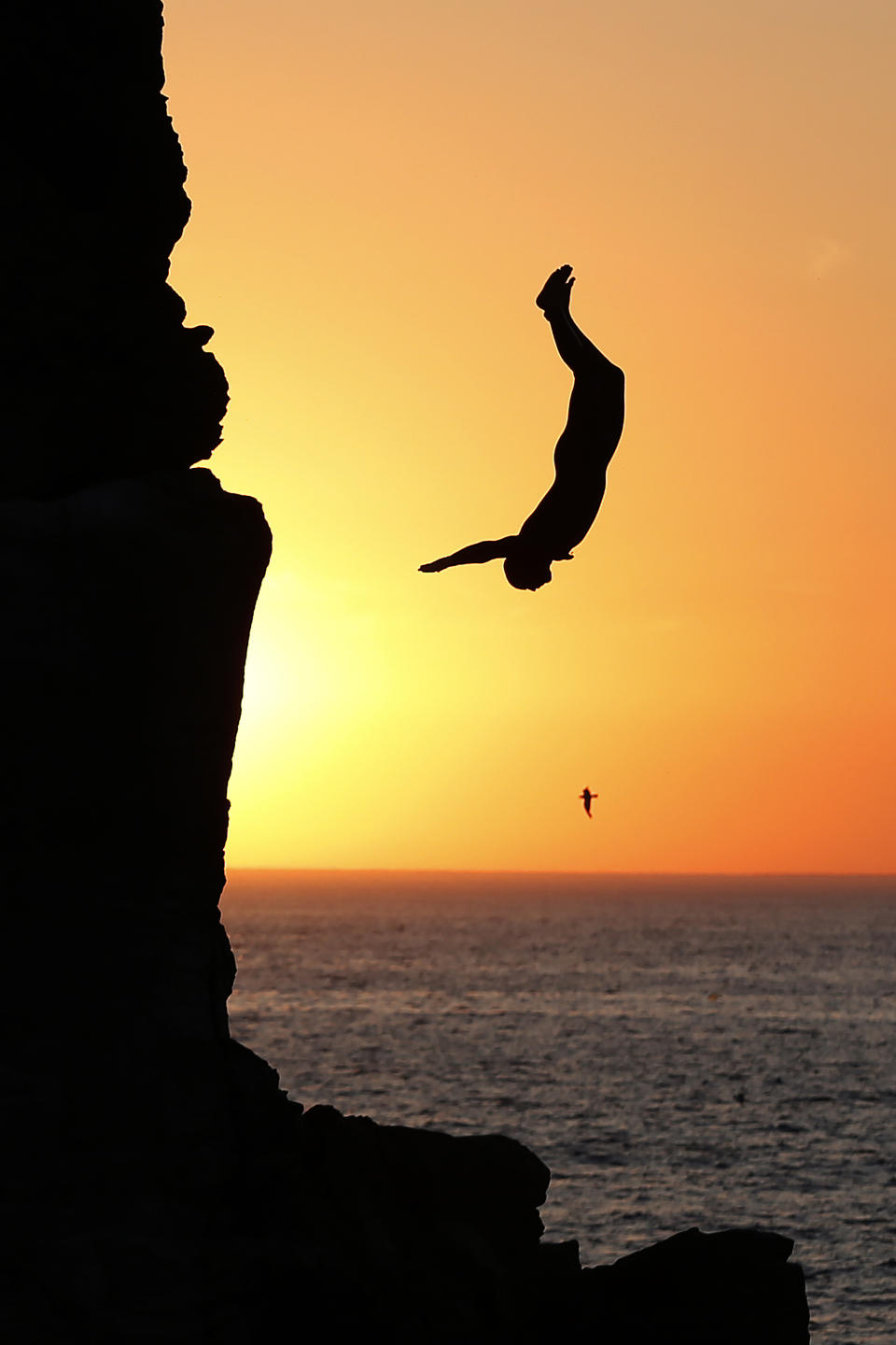 <p>A boy dives off rocks into the sea at sunset in Quiberon, north-western France on August 3, 2018. (Photo: Charly Triballeau/AFP/Getty Images) </p>