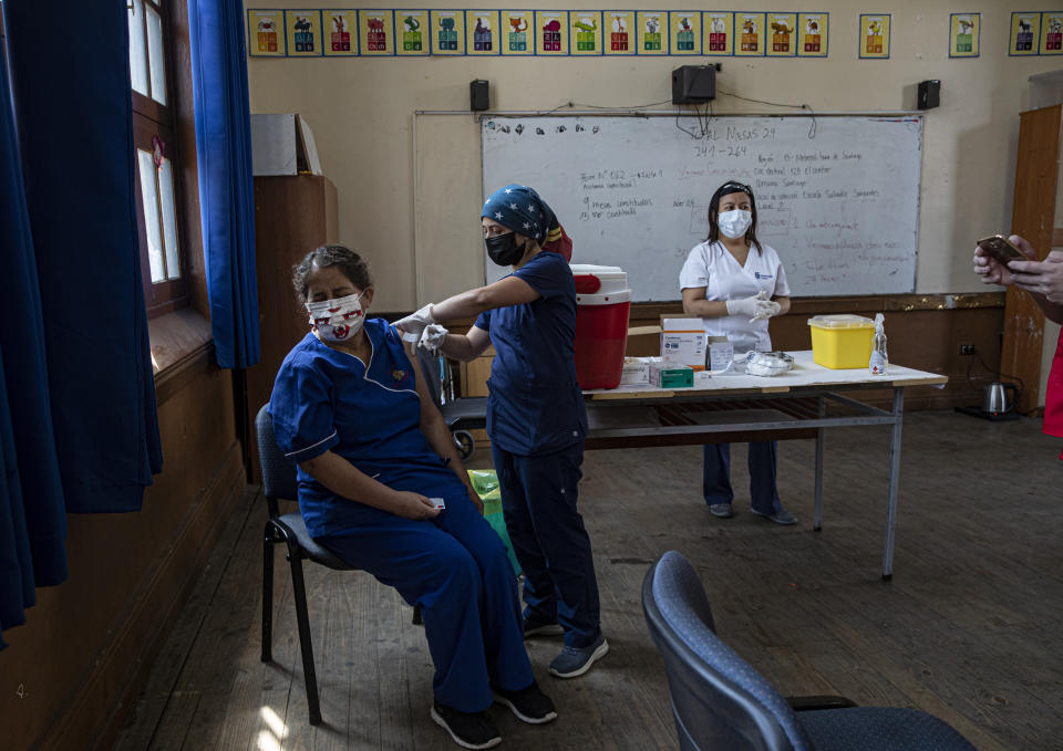 FILE - In this Monday, Feb. 15, 2021, file photo, a teacher receives a shot of the CoronaVac vaccine for COVID-19, by China's Sinovac Biotech, at Salvador Sanfuentes public school during the start of the vaccinations for educators in Santiago, Chile. It wasn’t until Sinovac swooped in with 4 million doses in late January that Chile began inoculating its population of 19 million with impressive speed. (AP Photo/Esteban Felix)