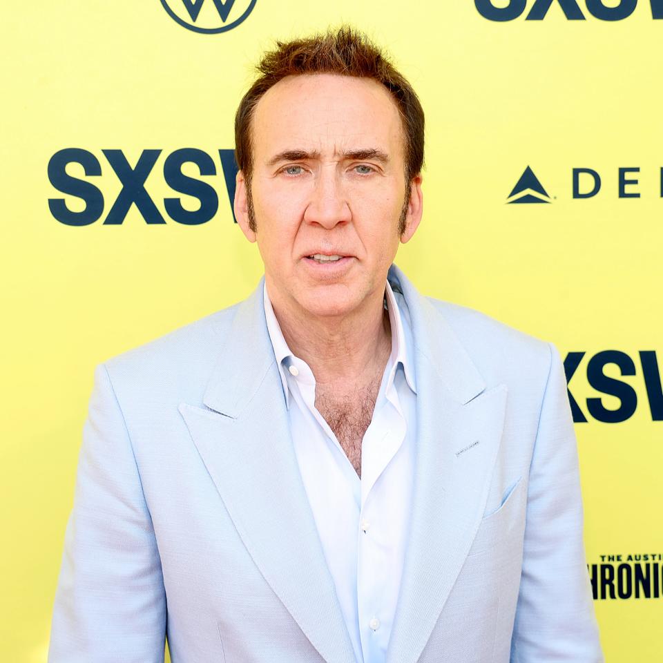 Nicolas Cage in a light blue suit with an unbuttoned white shirt at an event