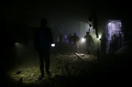 People are seen inspecting the damage after an air raid in the besieged town of Douma in eastern Ghouta in Damascus, Syria February 8, 2018. REUTERS/Bassam Khabieh