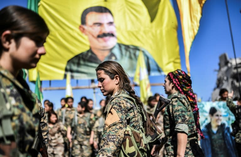 Female fighters of the Syrian Democratic Forces (SDF) gather during a celebration at Al-Naim square in Raqa, before a flag with the photograph of Turkey's jailed Kurdish leader Abdullah Ocalan, after retaking the city from the Islamic State group