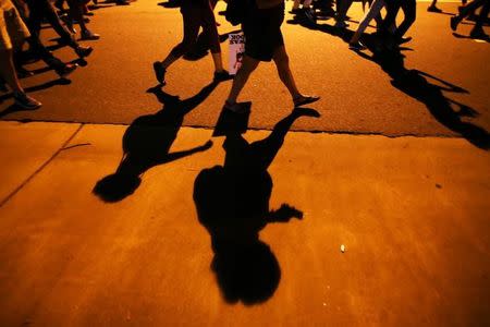 Protesters' shadows mark the sidewalk as they march during another night of protests over the police shooting of Keith Scott in Charlotte, North Carolina, U.S. September 24, 2016. REUTERS/Mike Blake