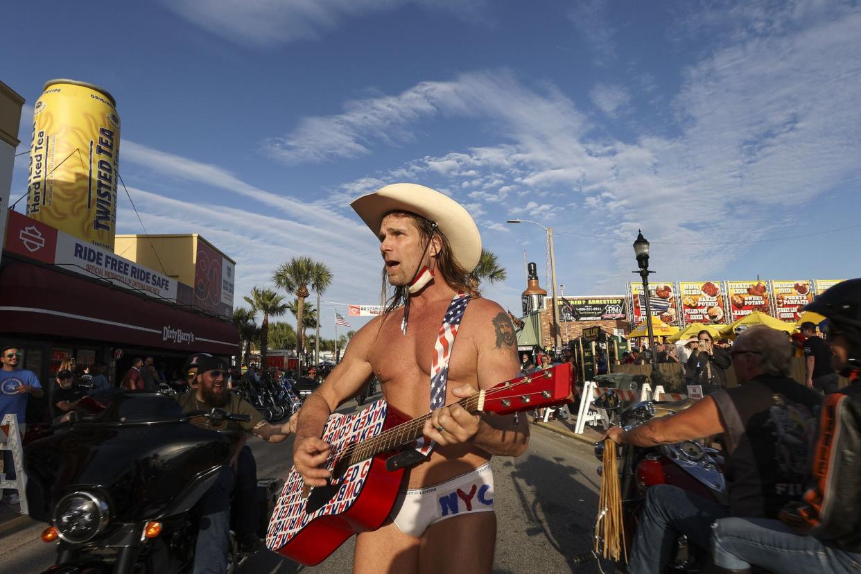 Robert Burck, better known as the “Naked Cowboy”, walks down the middle of Main Street performing in Daytona, FL during the start of Bike Week on March 5, 2021. Though Burck is famous for his street performances in New York City’s Times Square, he said this was his 21st time attending Bike Week. (Sam Thomas/Orlando Sentinel)