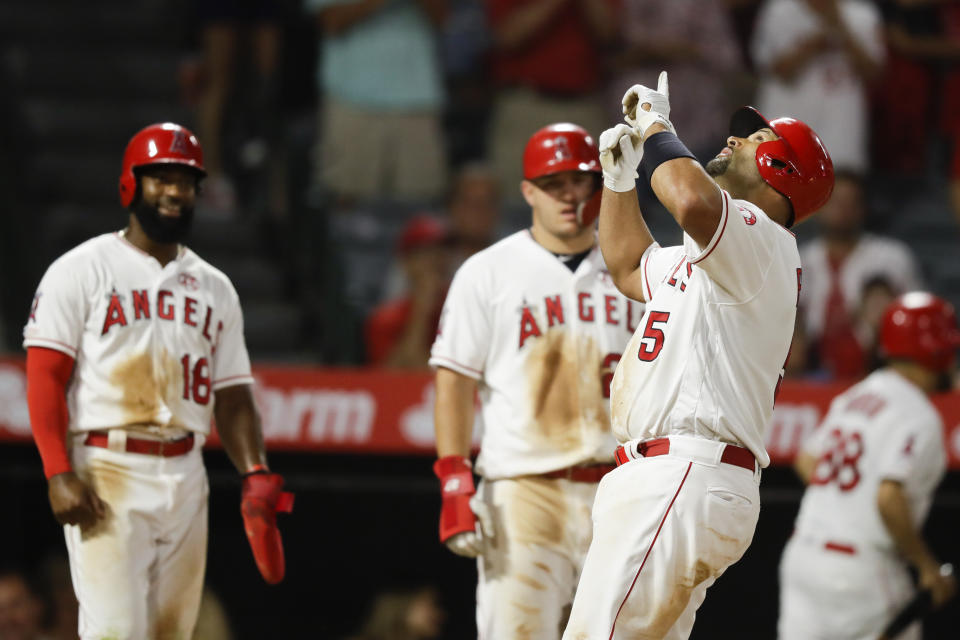 Los Angeles Angels' Albert Pujols, right, celebrates his three-run home run as Brian Goodwin, left, and Mike Trout watch, during the eighth inning against the Boston Red Sox in a baseball game in Anaheim, Calif., Saturday, Aug. 31, 2019. (AP Photo/Chris Carlson)