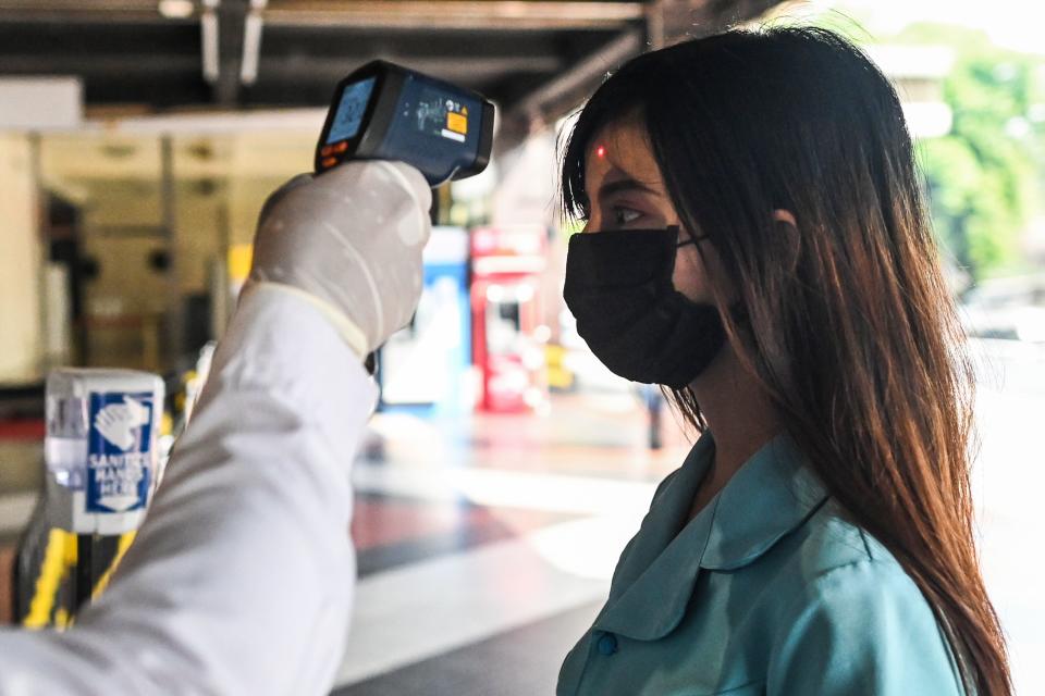 A woman's temperature is taken as a preventive measure against the COVID-19 coronavirus before entering a shopping mall in Yangon  on March 25, 2020. - Myanmar confirmed its first cases of of the deadly novel coronavirus on March 23  after weeks of increasing scepticism over the under-developed southeast Asian nation's claims to be free of the disease. (Photo by Ye Aung THU / AFP) (Photo by YE AUNG THU/AFP via Getty Images)