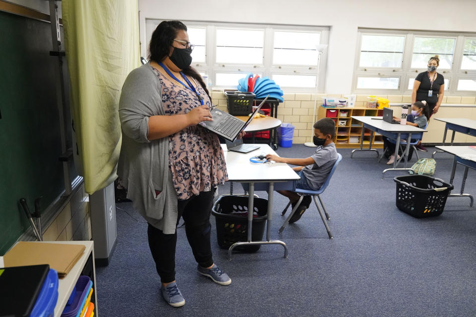 FILE - Teacher Jessica Flores directs students as they work on laptops in a classroom in Newlon Elementary School on, Aug. 25, 2020, in Denver, Colo., which is one of 55 Discovery Link sites set up by Denver Public Schools where students are participating in remote learning during the COVID-19 pandemic. Colorado lawmakers are considering joining eight other states in an agreement that would eliminate many of the requirements for teachers to get licensed when they move within the member states. (AP Photo/David Zalubowski, File)