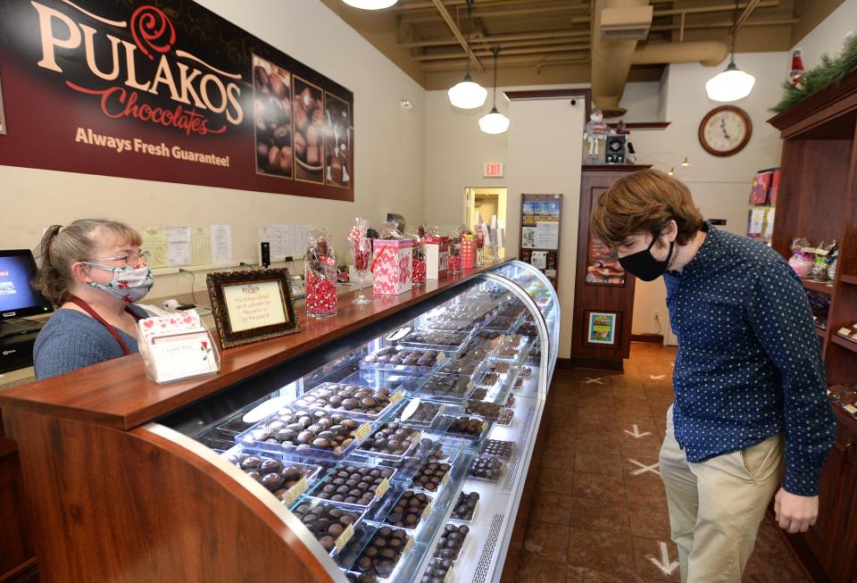 Susan Mazzone, manager at the Millcreek Mall Pulakos Chocolates, serves customer Andrew Sipple of Summit Township.