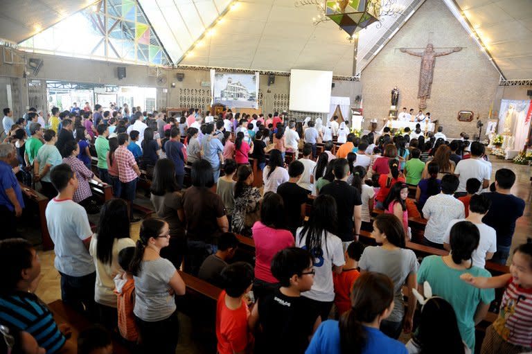 Catholics attend a mass in a small church in Manila on April 21, 2013. In cathedrals around the Philippines, huge black and red banners are asking the faithful to choose between "Team Life" and "Team Death", with priests warning the nation's soul is at stake. The signs are part of efforts by the Catholic Church to assert influence at next week's mid-term elections