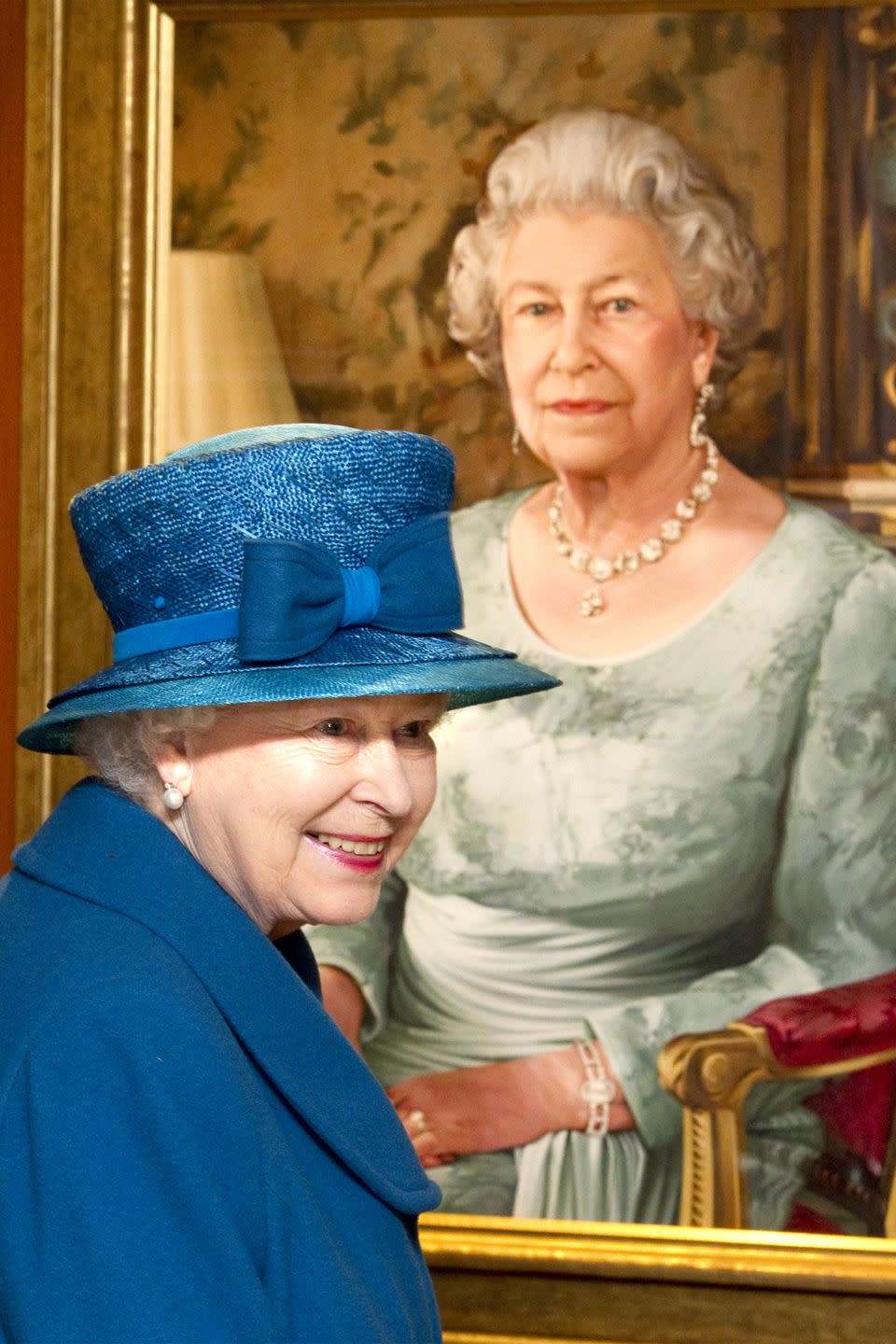 <p>QEII wore a blue jacket, matching hat, and pearl earrings as she looked at a commissioned portrait of herself in The Queen's Room at the Southampton docks.</p>