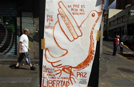 Pedestrians walk past a poster promoting peace at Chacao district in Caracas, February 27, 2014. REUTERS/Tomas Bravo