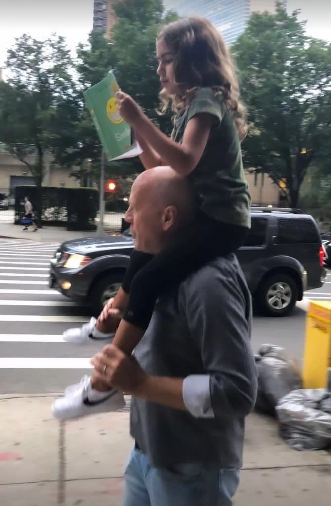 In the snap, the actor held his daughter on his shoulders as she read a book. @emmahemingwillis/Instagram