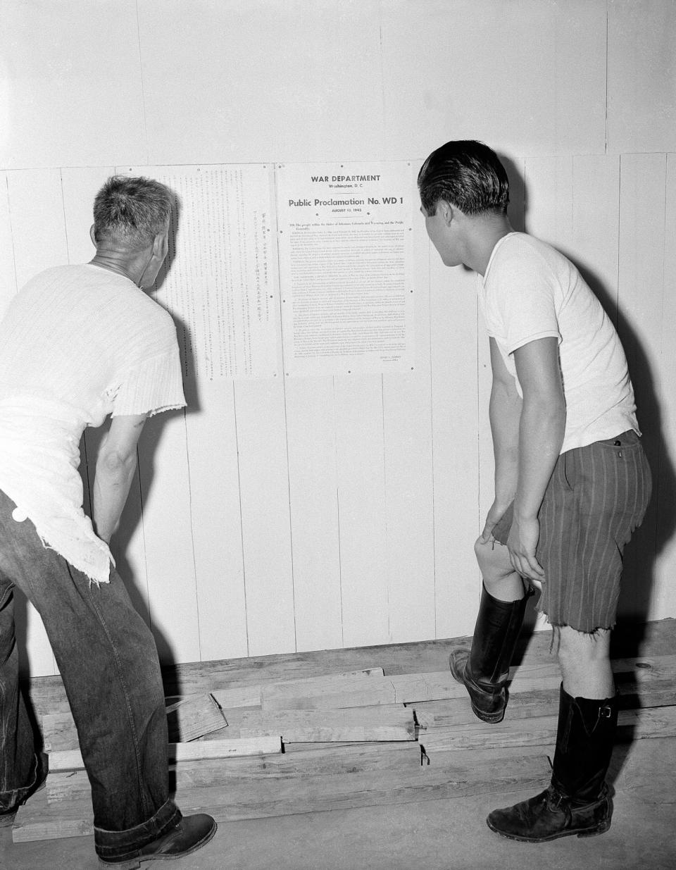 <p>Interned Japanese men read President Roosevelt’s proclamation on their evacuation, posted on the wall at Rohwer Relocation Center near McGehee, Ark., Sept. 21, 1942. (AP Photo/Horace Cort) </p>