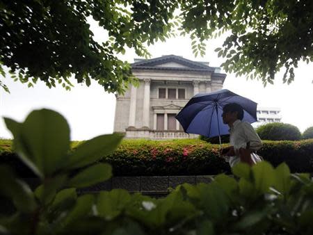 A pedestrian holding an umbrella walks past the Bank of Japan building in Tokyo June 11, 2013. REUTERS/Yuya Shino