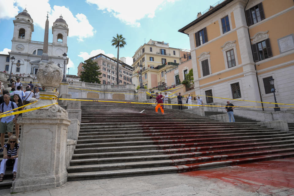 Rome municipality workers clean the Spanish Steps after activists dumped red paint over them protesting against violence on women, in Rome, Wednesday, June 26, 2024. (AP Photo/Andrew Medichini)