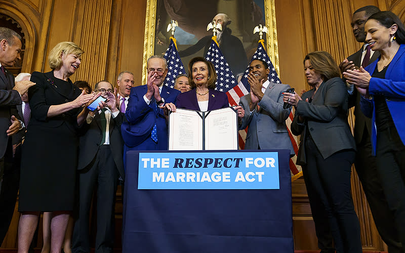 Speaker Nancy Pelosi (D-Calif.) holds the Respect for Marriage Act during an enrollment ceremony at the Capitol on Dec. 8. <em>Greg Nash</em>