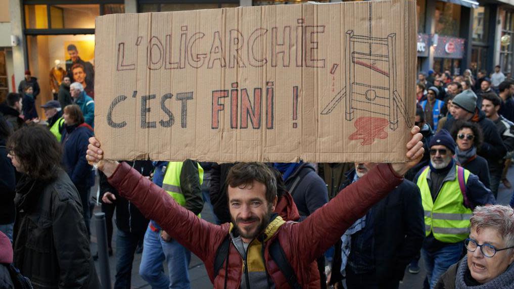 Un hombre con un cartel que dice, en francés, que la oligarquía ha terminado