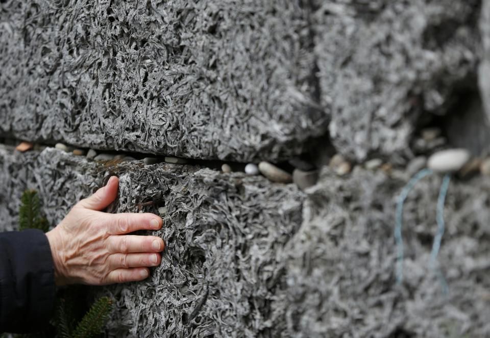 A survivor touches the 'Wall of Death' in the former Nazi German concentration and extermination camp Auschwitz in Oswiecim