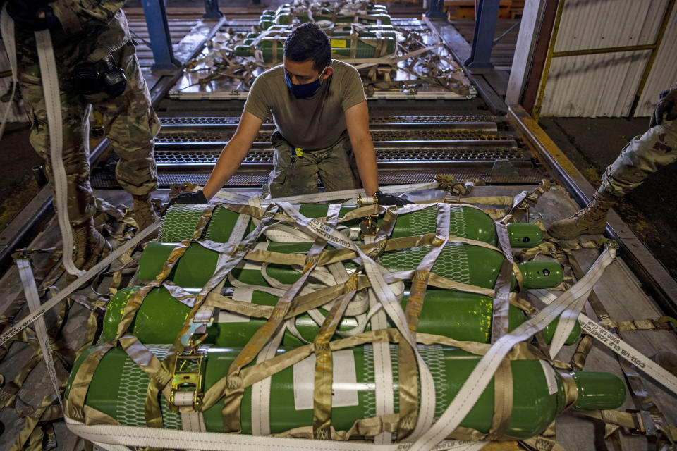 In this photo provided by the U.S. Air Force, Airman 1st Class Fernando Beltran secures oxygen cylinders to a pallet on April 28, 2021, at Travis Air Force Base, Calif. The United States is donating medical supplies to assist the country of India in its fight against COVID-19. The donation of 440 oxygen cylinders and regulators, one million N95 masks and one million COVID-19 rapid diagnostic kits, will be transported to India aboard a U.S. Air Force C-5M Super Galaxy aircraft. (Nicholas Pilch/U.S. Air Force via AP)