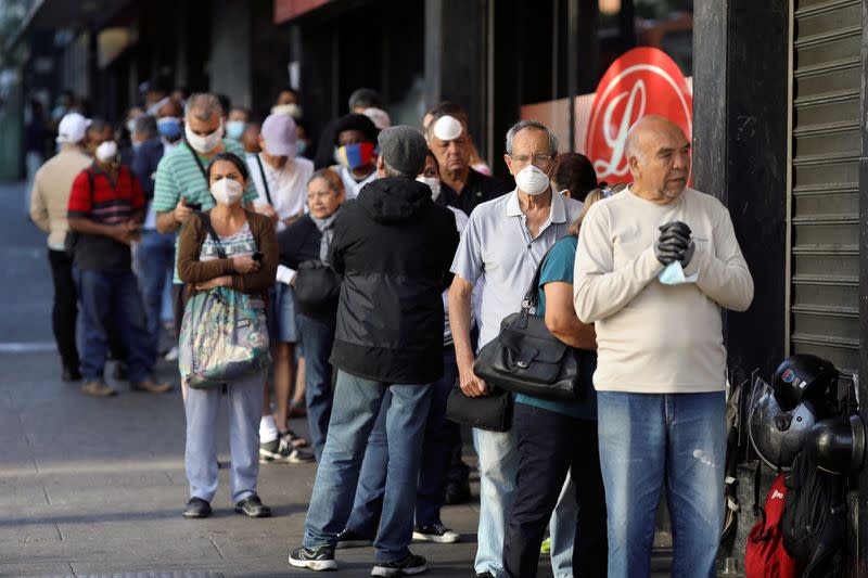 People queue in front of a supermarket during the first day of a national quarantine in response to the spreading coronavirus disease (COVID-19) in Caracas