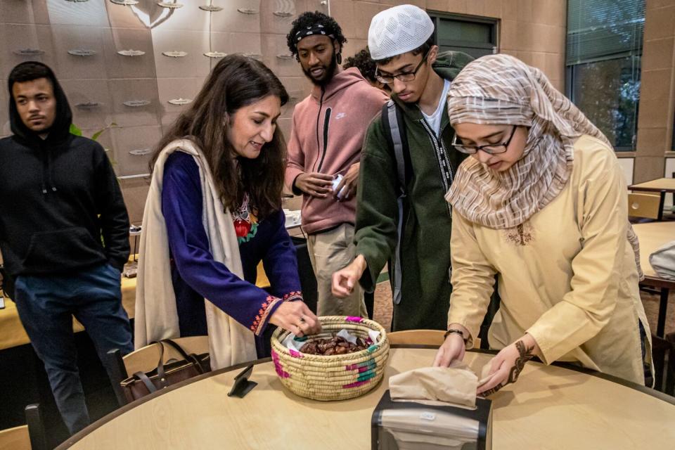 Shaila Andrabi and Muslim students gather around a round table; a couple reach into a basket with dates.